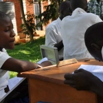 A visually-impaired student takes down the notes from one of the sighted girls.