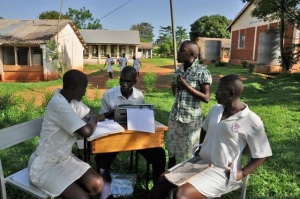 One of our students, Kaka, takes the notes on his Brailler from a sighted girl.