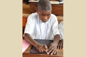 Solomon, visually impaired, using a slate and stylus to take notes