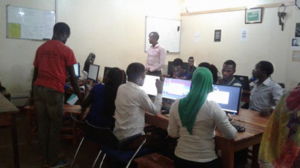 Students around computer monitors learning programming